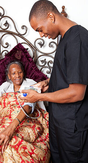Caregiver checking a client's vitals at her bedside