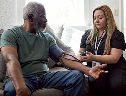 Caregiver monitoring a senior man's blood pressure